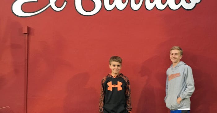 Aidan and Ian in front of red wall of El Burrito